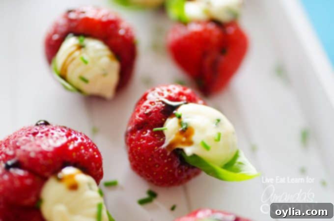 A close up photo of strawberries stuffed with whipped brie and topped with a basil leaf.