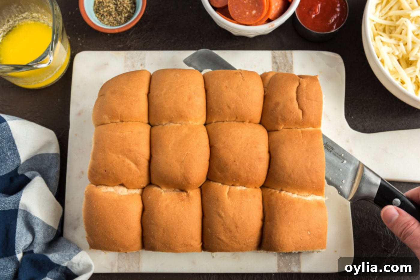 Chef slicing a block of slider buns horizontally in half