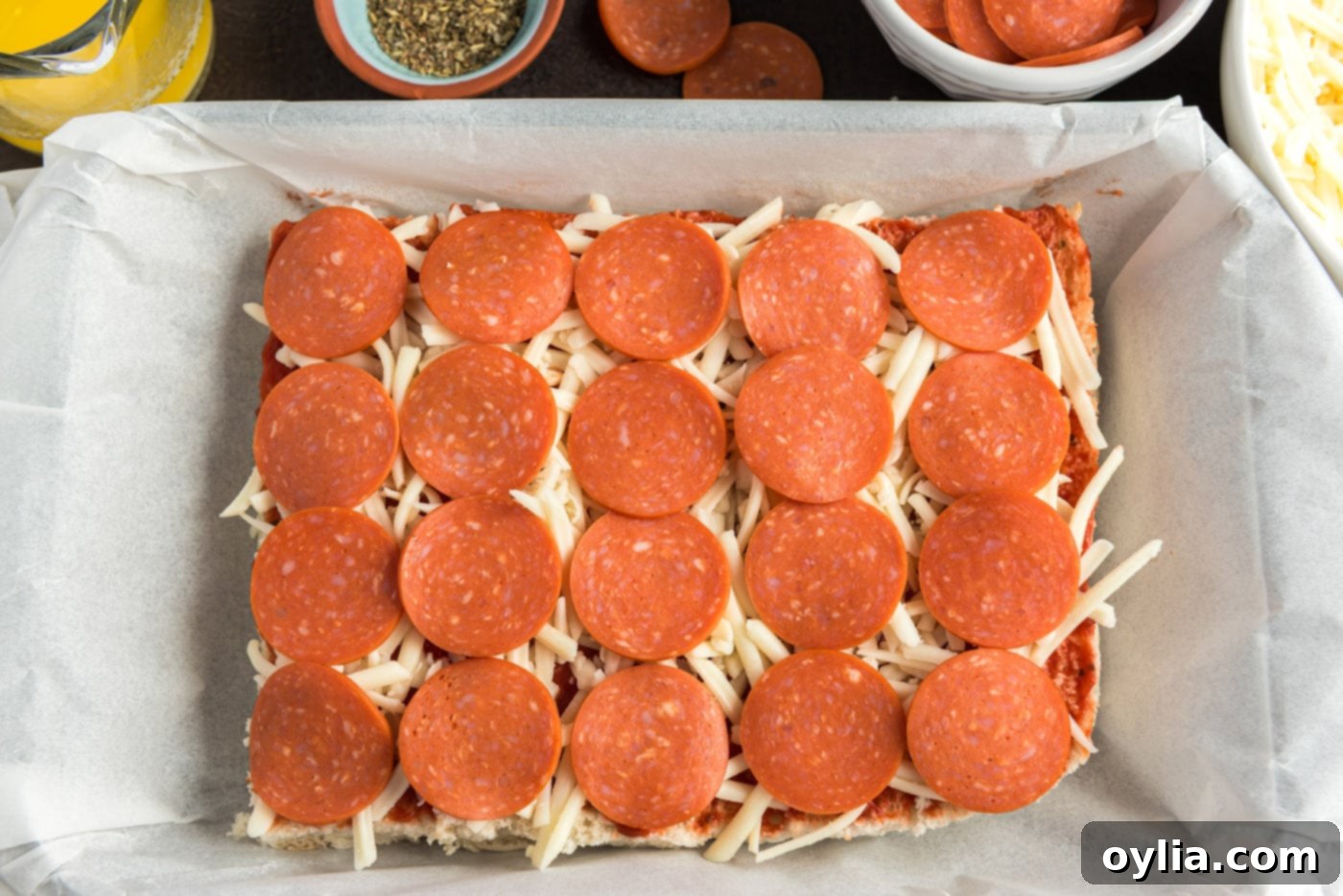 Layer of pepperoni slices arranged over mozzarella cheese on slider buns