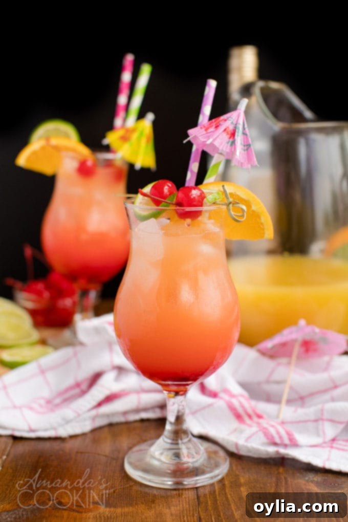 Two glasses of Caribbean Rum Punch, beautifully lit against a dark background, showcasing their vibrant colors.