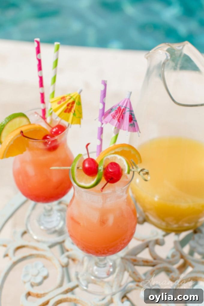 Two glasses of vibrant rum punch, perfectly garnished, sitting invitingly by the pool.