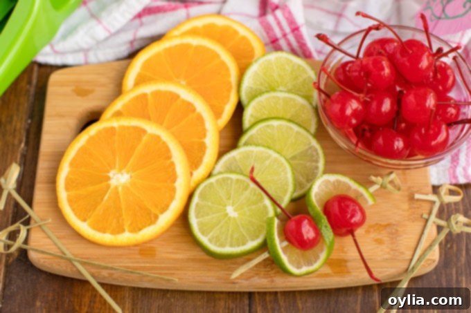 Sliced oranges and limes with maraschino cherries neatly arranged on a cutting board, ready for garnish.