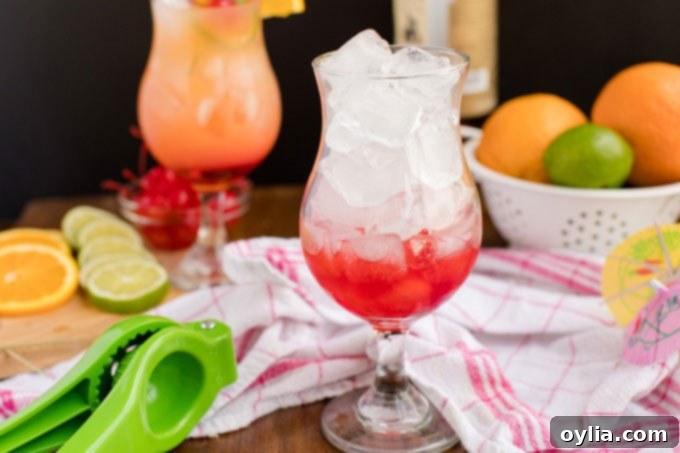 A hurricane glass filled with ice, showing the vibrant red grenadine syrup settled at the bottom, awaiting the rum punch.