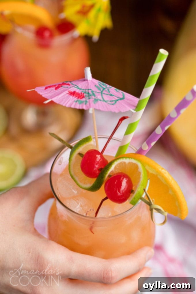 A hand holding a perfectly garnished glass of rum punch, ready to be enjoyed by the pool or at a summer party.