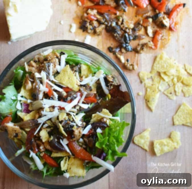 A vibrant Chicken Fajita Salad in a white bowl, garnished with lime wedges