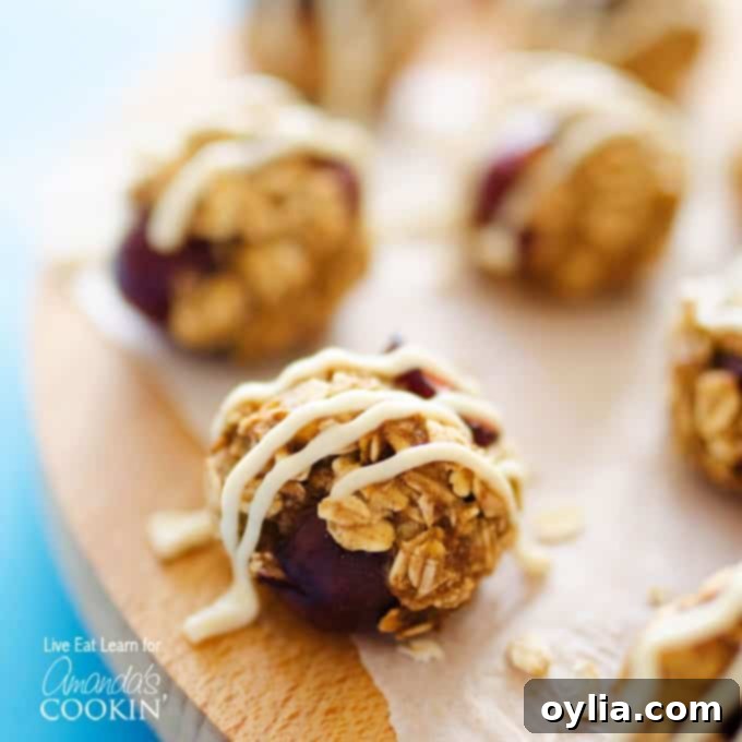 A close up photo of cherry cheesecake energy balls drizzled with cream cheese frosting.