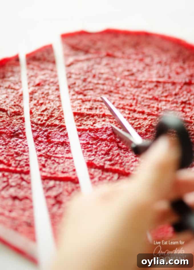 A close up of homemade fruit roll ups being cut into strips.