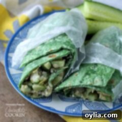 Two halves of a Mediterranean wrap in wax paper resting next to each other on a blue and white plate. This image is the main recipe photo.