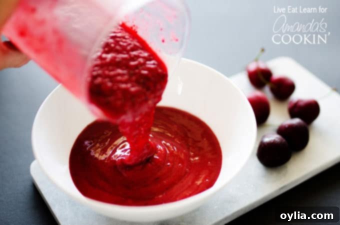 A close up photo of the vibrant purple stone fruit smoothie being poured into a white bowl, showcasing its thick and creamy texture, ready for toppings.