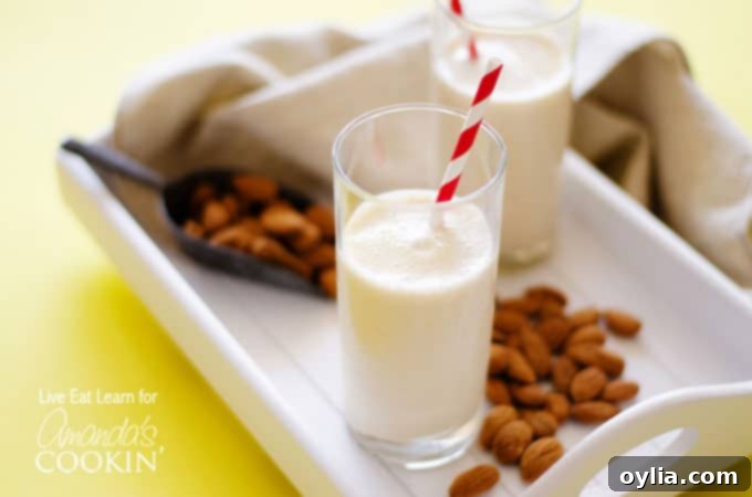An almond maple smoothie resting on a white plate with scattered almonds.