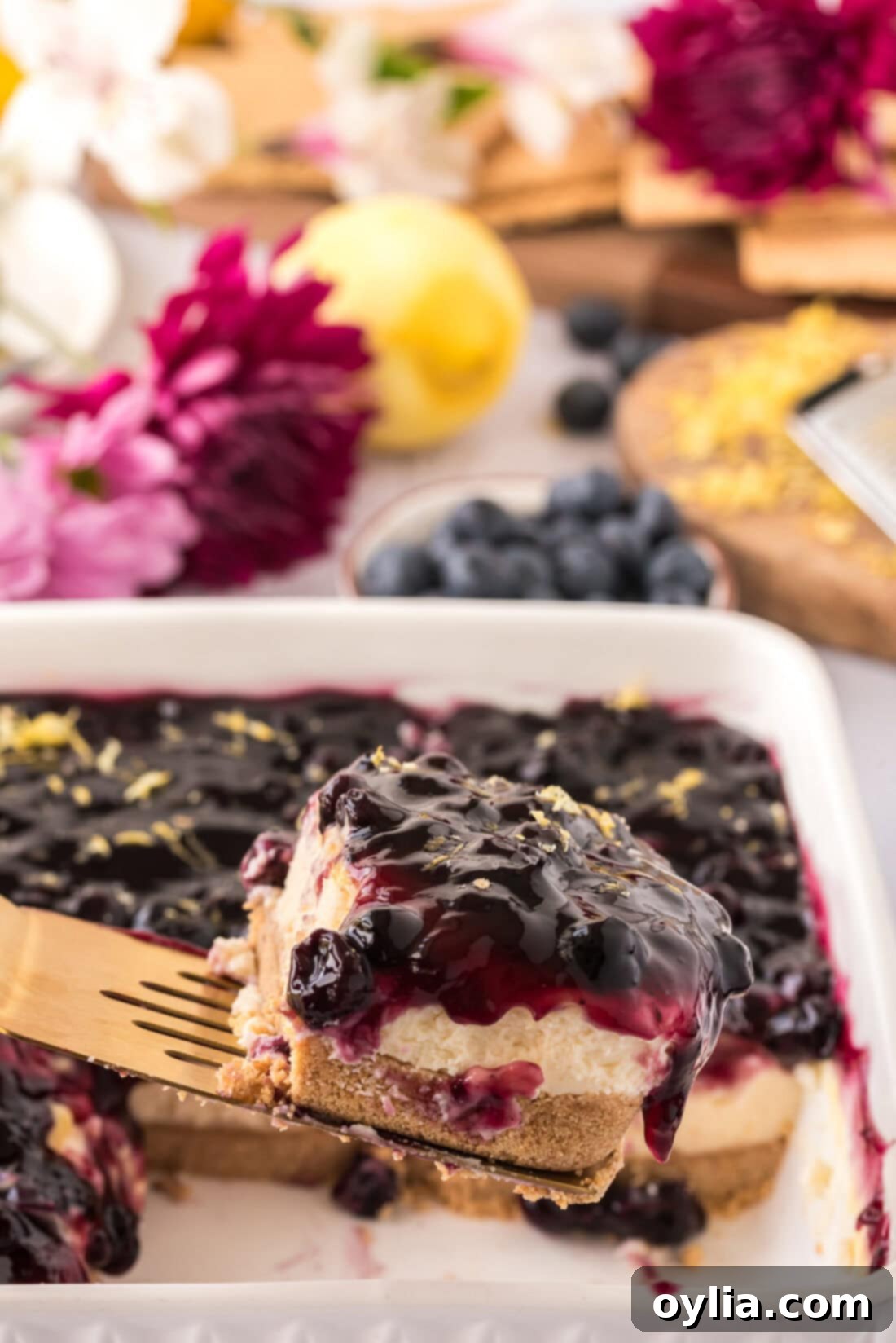 Spatula lifting up a slice of No Bake Blueberry Cheesecake, showcasing its creamy layers and blueberry topping