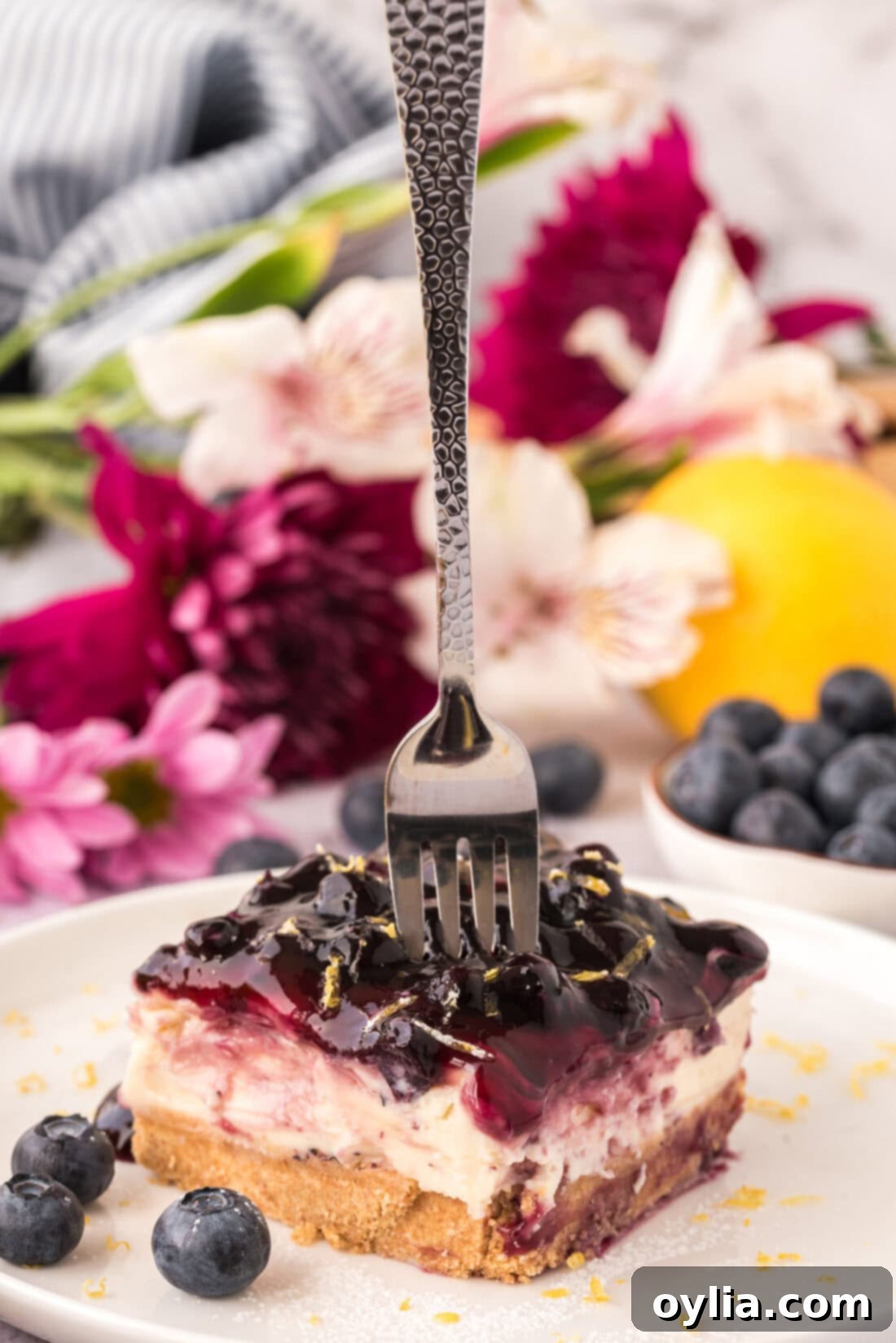 Fork pressing into a slice of No Bake Blueberry Cheesecake, showing the distinct layers