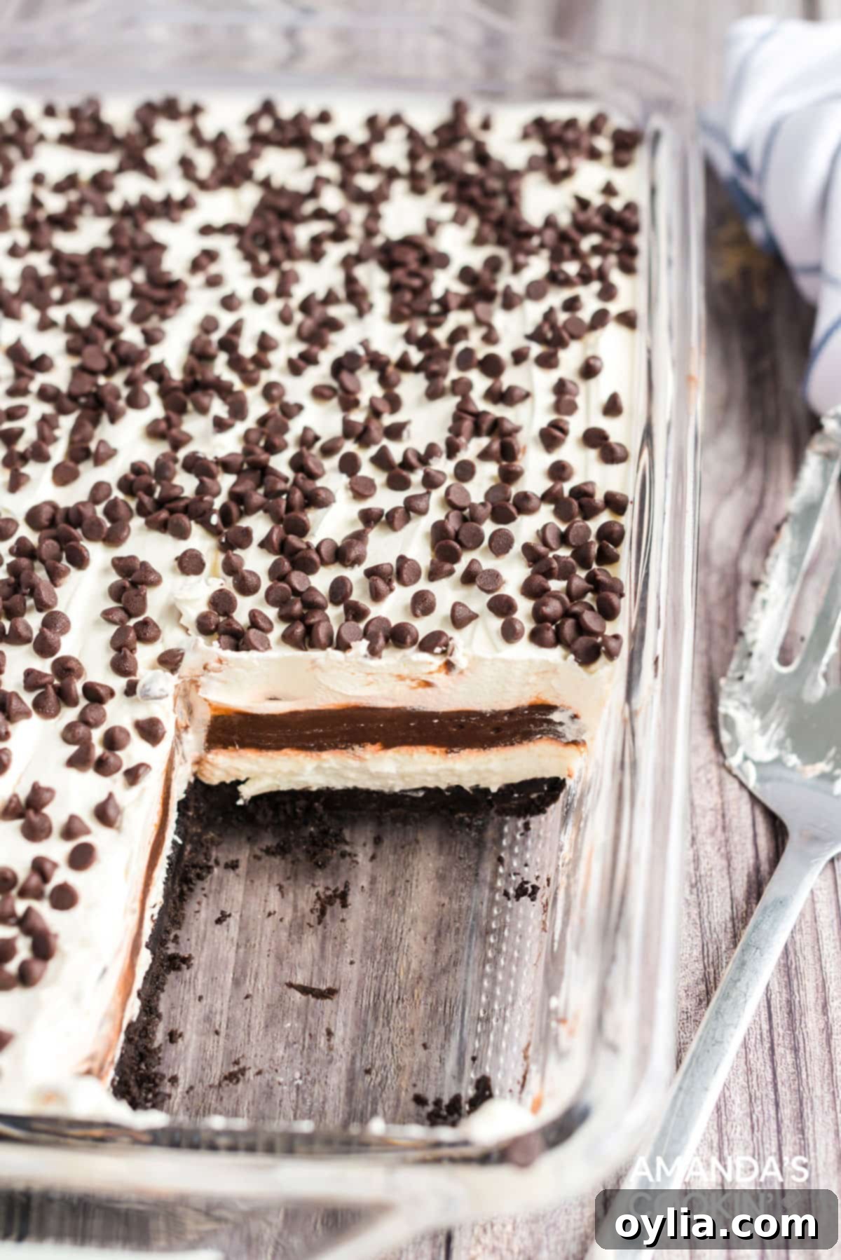 Chocolate lasagna is a no-bake layered dessert made with cookies, cream cheese, whipped cream and chocolate pudding. It's a chocolate dessert dream! pan of chocolate lasagna with a slice removed, showing all layers clearly