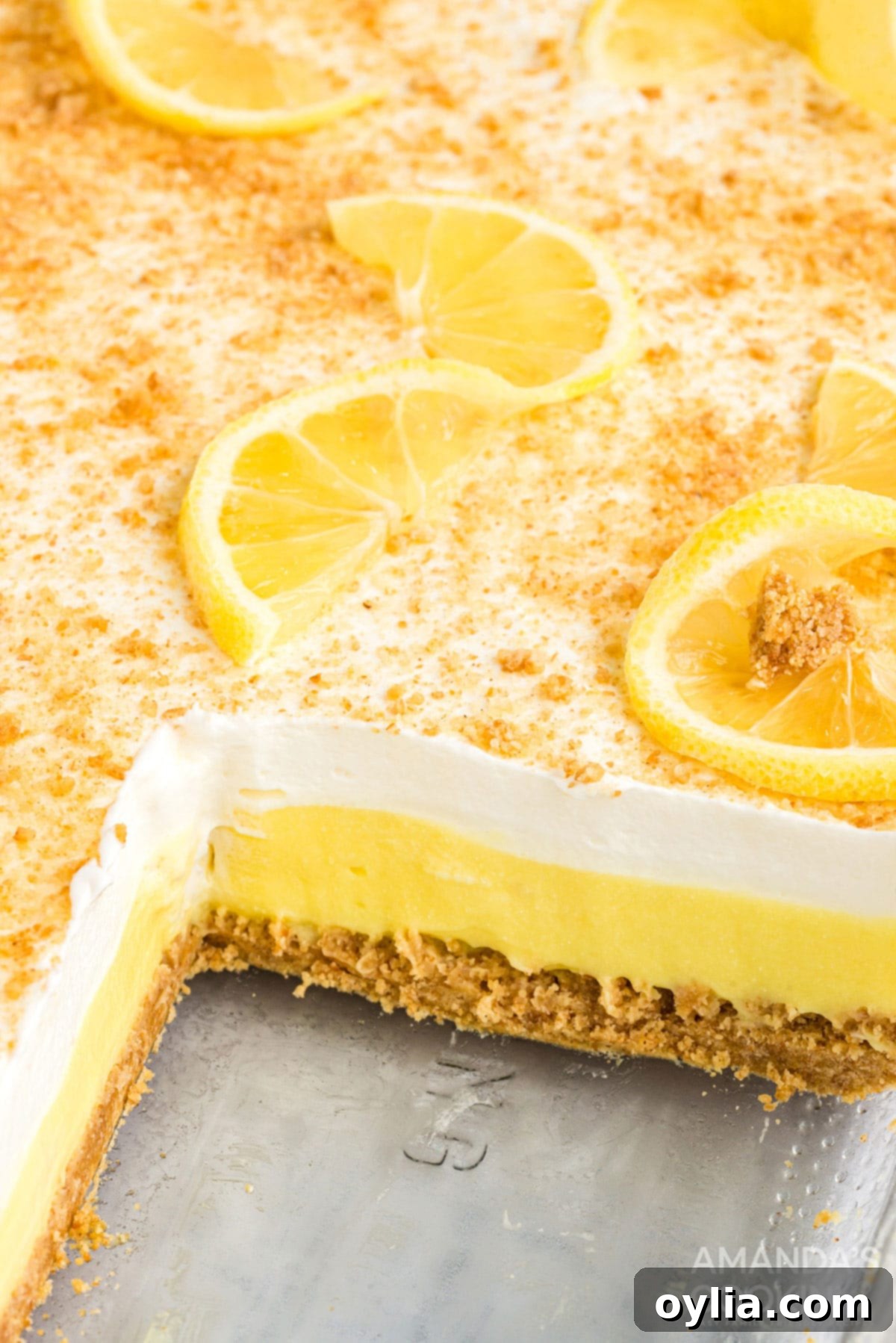 layered lemon dessert in a pan with a slice removed