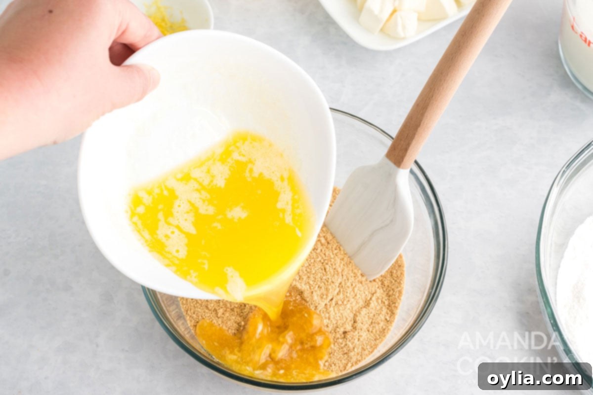 pouring melted butter into a bowl of graham cracker crumbs