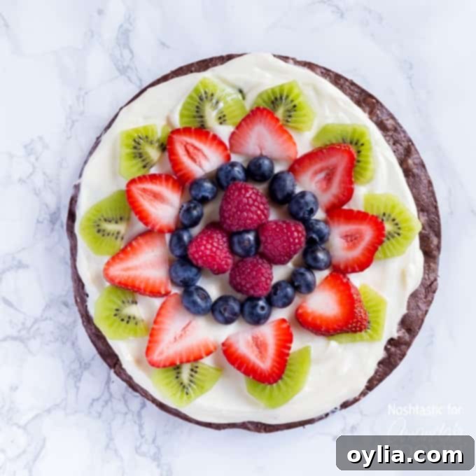 An overhead of cut up fruit on top of a brownie pizza.