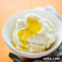 Velvety Cauliflower Mash 7 A white bowl filled with cauliflower mashed potatoes and melted butter on top.