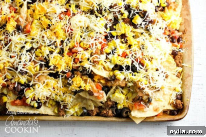 A close up overhead  of loaded nachos on a baking sheet.