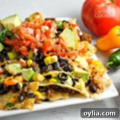 Ultimate Nacho Feast 9 A close up of loaded nachos on a white plate.