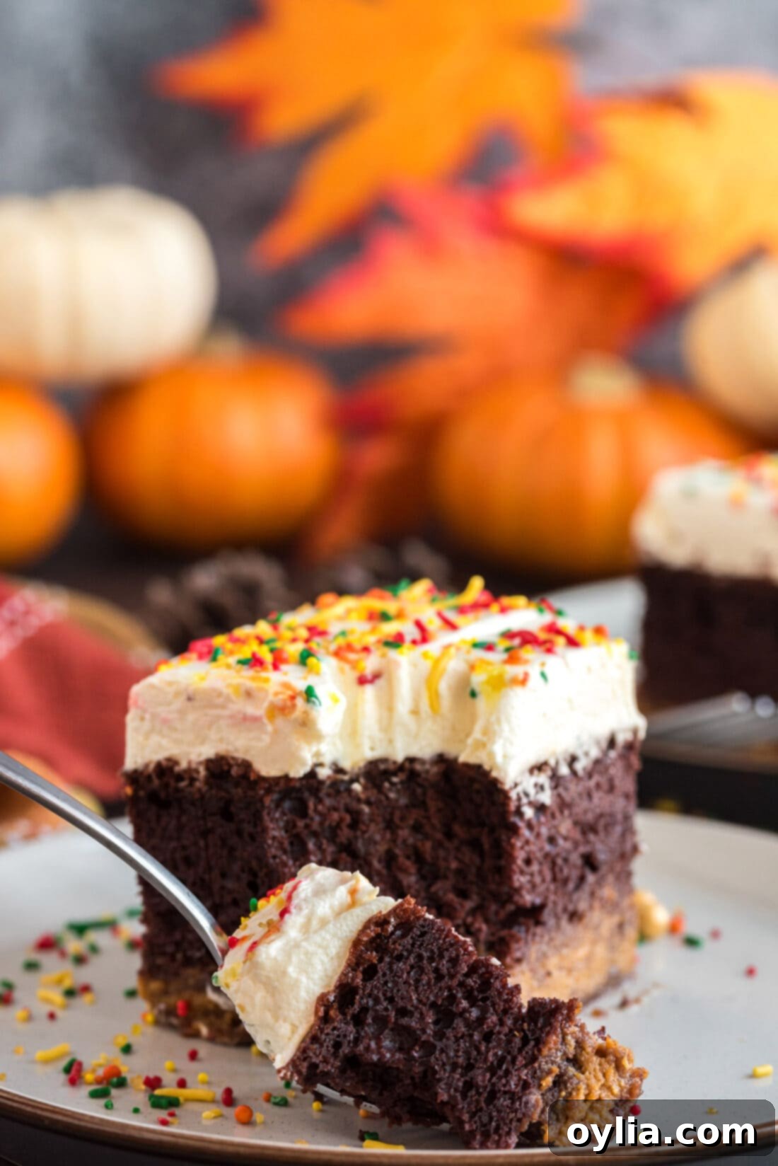 Piece of Chocolate Pumpkin Magic Cake on a plate with a fork taking a bite, showing all three layers clearly