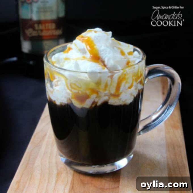 A salted caramel coffee cocktail in a clear mug with whipped cream and drizzled caramel on top.
