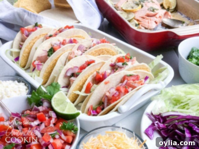 A beautifully arranged casserole dish filled with ready-to-serve salmon tacos, showcasing the vibrant fillings and warm shells, with a few lemon and lime wedges for extra zest.