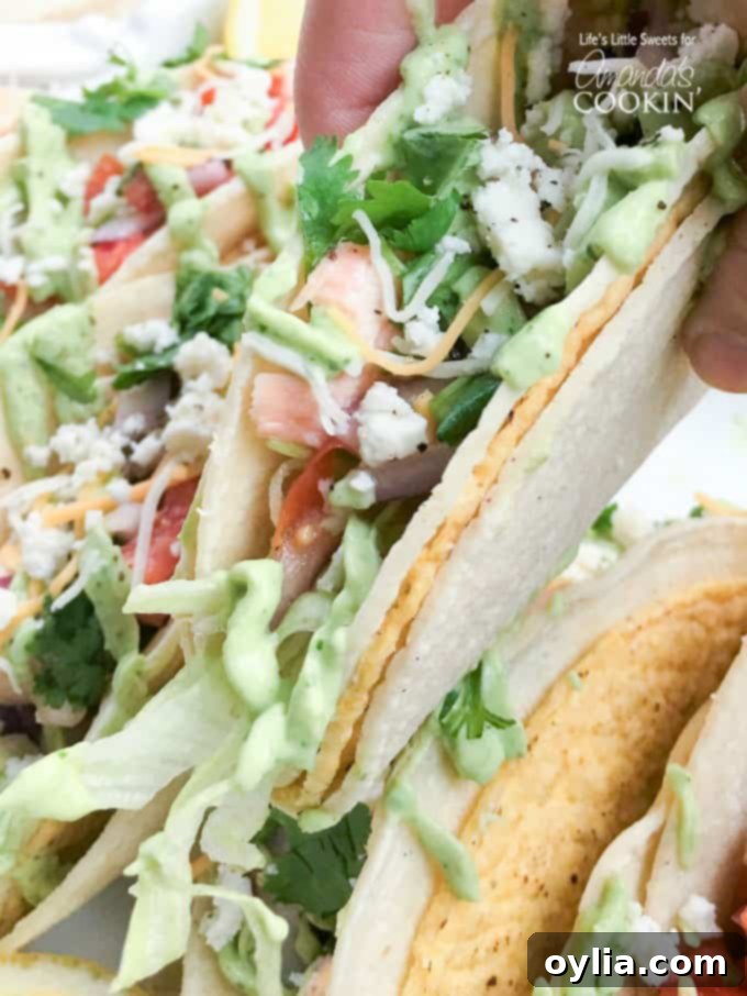 A close-up photo of a single salmon taco held in hand, showcasing the perfectly flaked salmon, colorful salsa, and creamy avocado sauce spilling slightly from a warm tortilla.