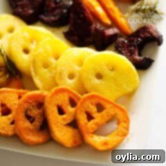 A close up photo of roasted Halloween vegetables laying on a platter, showcasing the fun shapes like jack-o-lanterns, ghosts, and witch hats.
