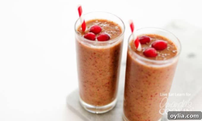 A close up of two cranberry smoothies in glasses with cranberries on top and served with a straw, ready to be enjoyed.