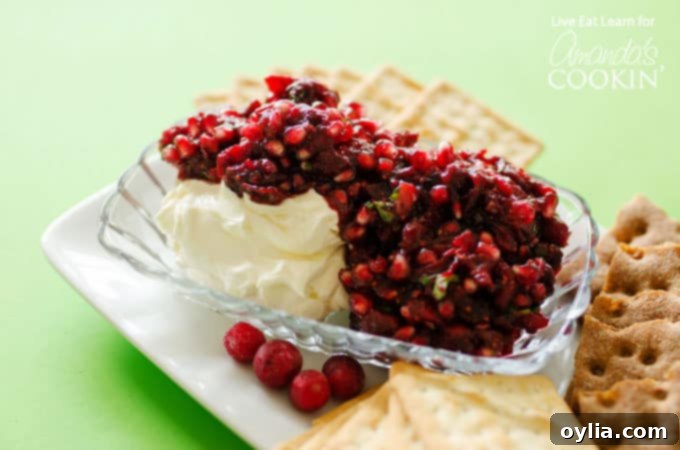 A top-down view of cranberry salsa generously spooned over cream cheese, surrounded by a variety of crackers, creating an inviting holiday appetizer spread.