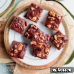 An overhead of chocolate walnut fudge squares on a white and gold plate.