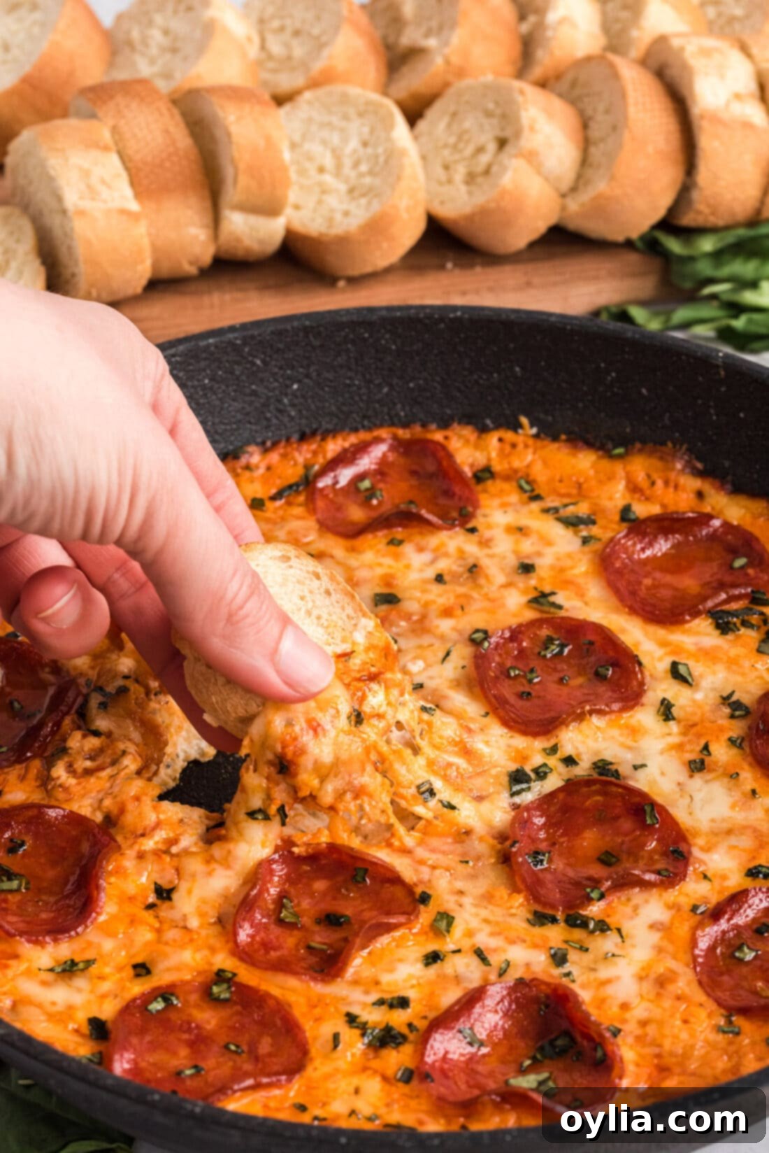 Ultimate Pizza Dip 2 dipping bread into pizza dip, showing layers of cheese and sauce