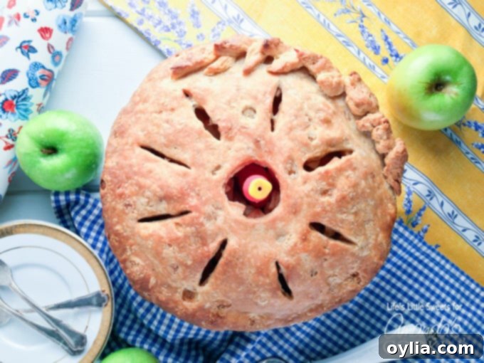 An overhead view of a perfectly baked homemade apple pie, showcasing its intricate crust design and golden finish.