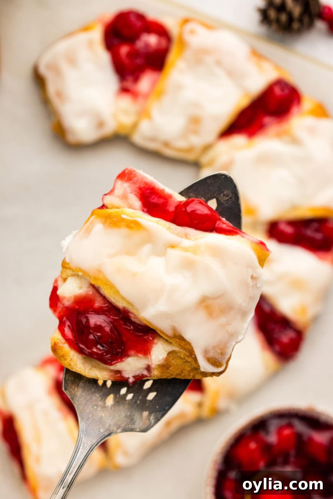 A slice of Candy Cane Danish held above the rest of the danish, showcasing its flaky layers and delicious filling