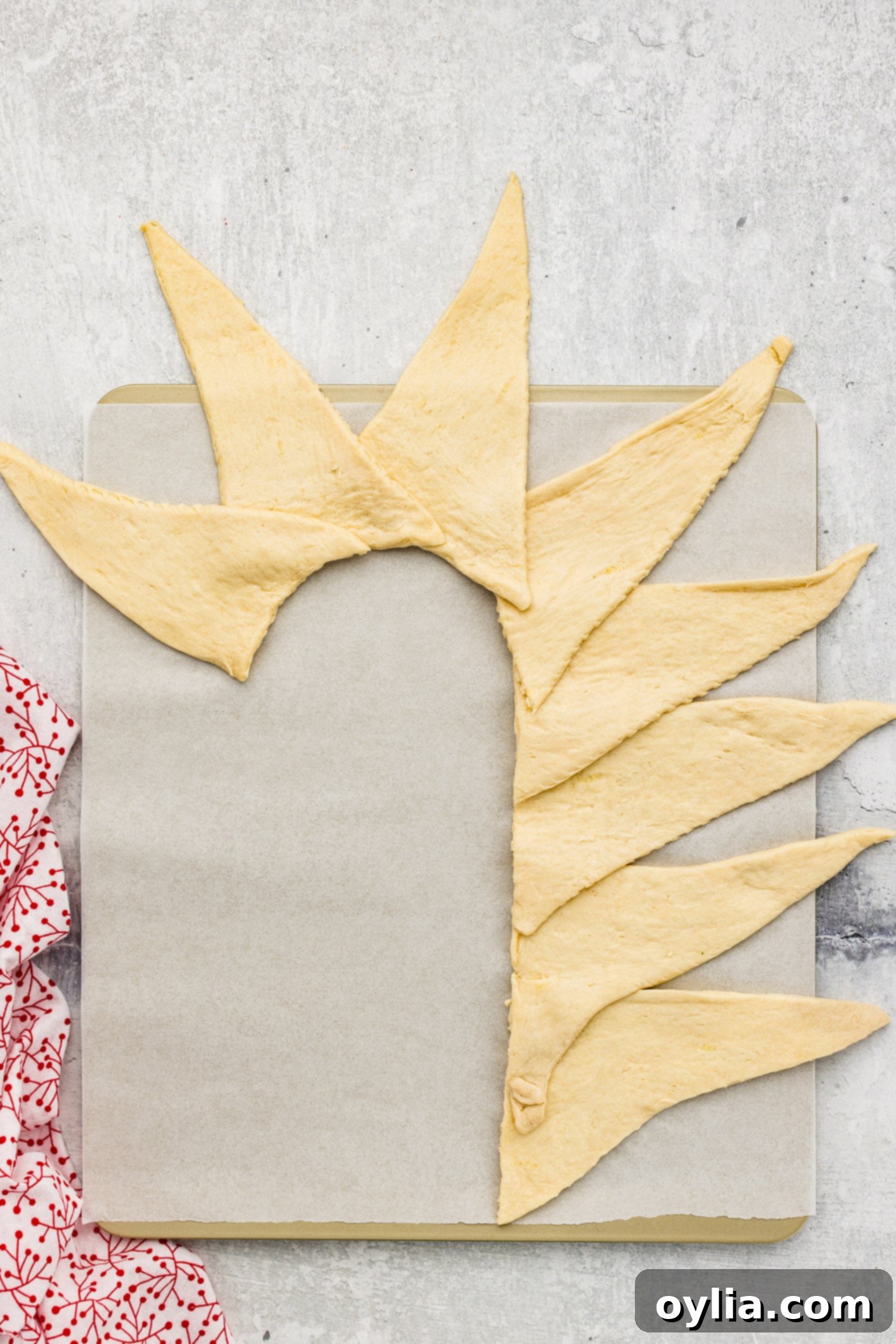 Crescent roll triangles arranged and shaped like a candy cane on parchment paper