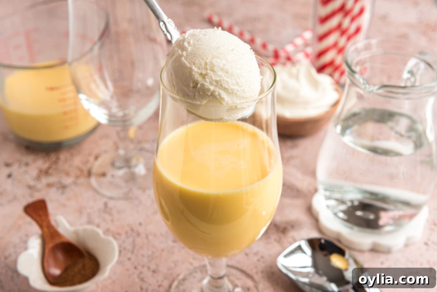 adding a scoop of vanilla ice cream to glass with eggnog