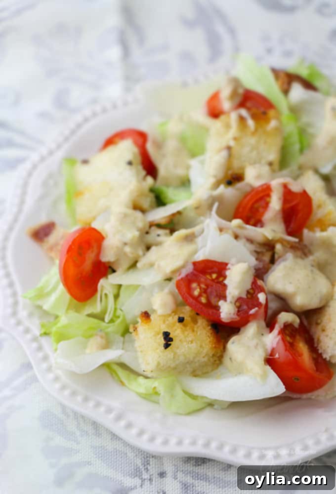 A close up of a tomato Caesar salad on a white plate.