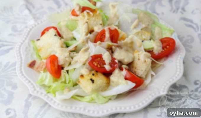 A close up of a tomato Caesar salad on a white plate.
