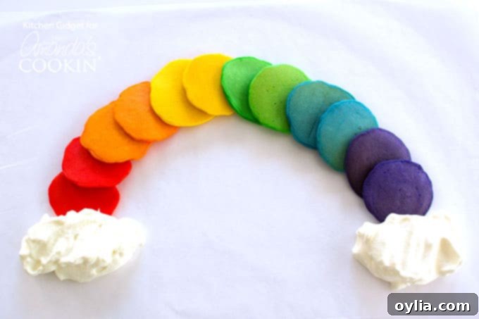 Colorful pancakes stacked to form a rainbow, served on a white plate