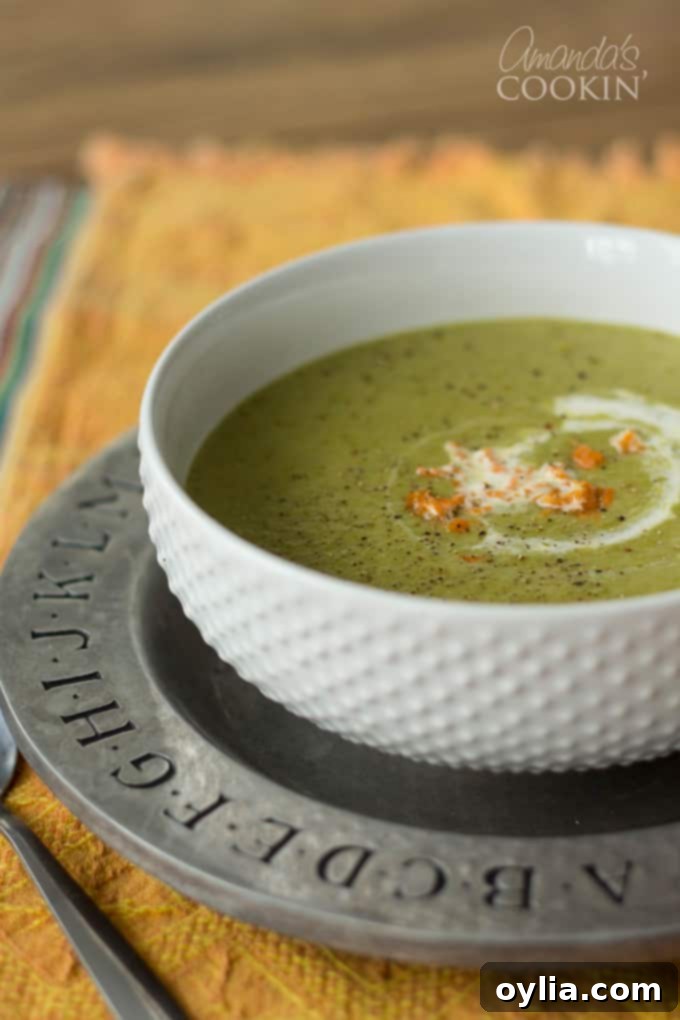 A white bowl filled with cream of asparagus soup, garnished with fresh herbs.