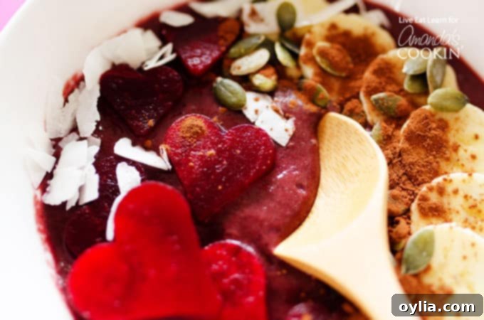 A wooden spoon scooping into a rich, velvety red smoothie bowl, showing its thick and creamy texture with swirls of deep red and hints of chocolate.