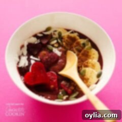 A perfectly blended red velvet smoothie bowl, topped with festive heart-shaped fruit and a sprinkle of cocoa, ready to be enjoyed.