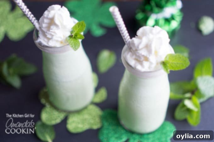 Two naturally green shamrock shakes garnished with fresh mint leaves and whipped cream, ready for St. Patrick's Day celebration.