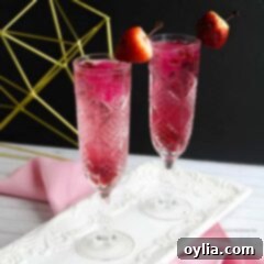 Glass of sparkling pink Cupid's Cocktail with a strawberry garnish