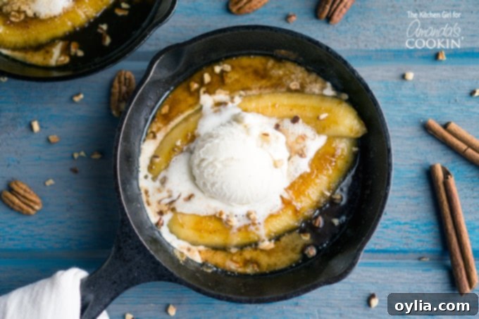 A mouth-watering image of the finished single serve bananas foster, presented in a small cast iron skillet. The caramelized bananas are bathed in a rich, dark rum-infused sauce, topped with a generous scoop of melting vanilla ice cream and a sprinkle of chopped pecans.