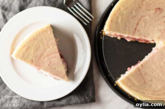 A delightful composition featuring a single, perfect slice of strawberry swirl cheesecake on a white plate, placed alongside the magnificent whole baked cheesecake, highlighting its impressive height and creamy texture.