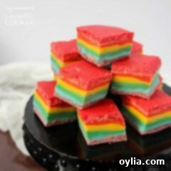 A close up of rainbow fudge cubes stacked on a black circular platter.