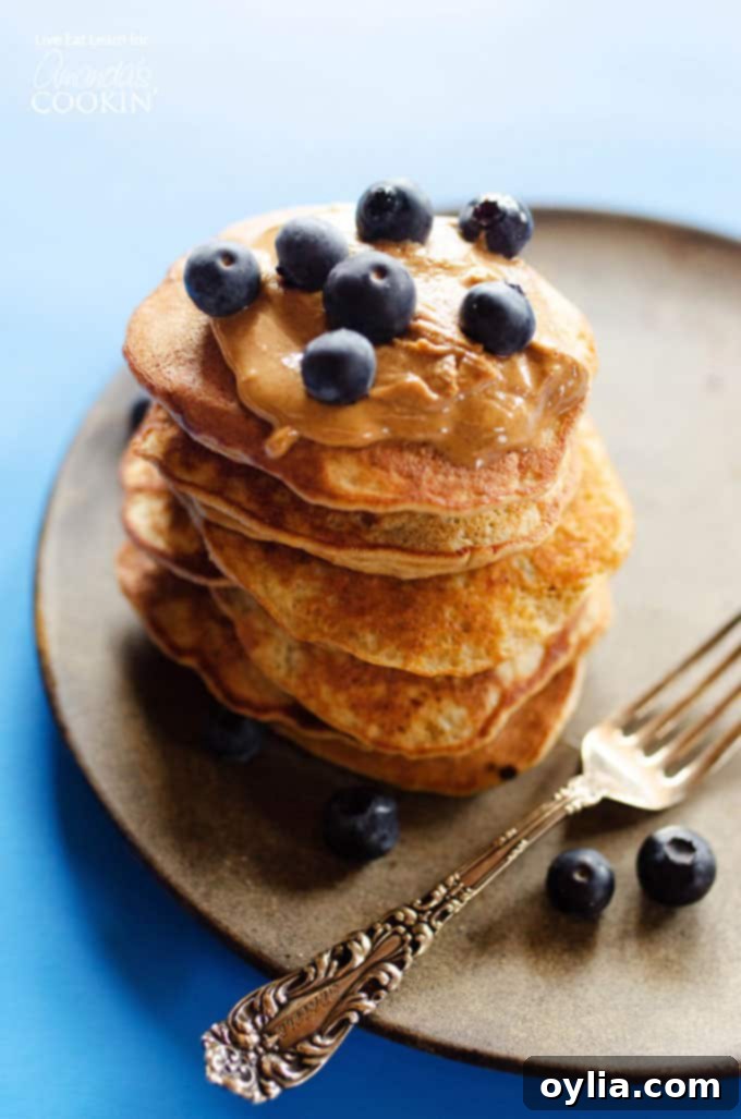 stack of fluffy flourless banana pancakes with blueberries on top on a brown plate