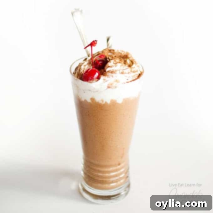 A single chocolate nice cream milkshake, garnished with a bright red maraschino cherry, sits ready for a refreshing sip.