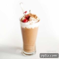 A perfectly blended chocolate nice cream milkshake, adorned with a bright red maraschino cherry.